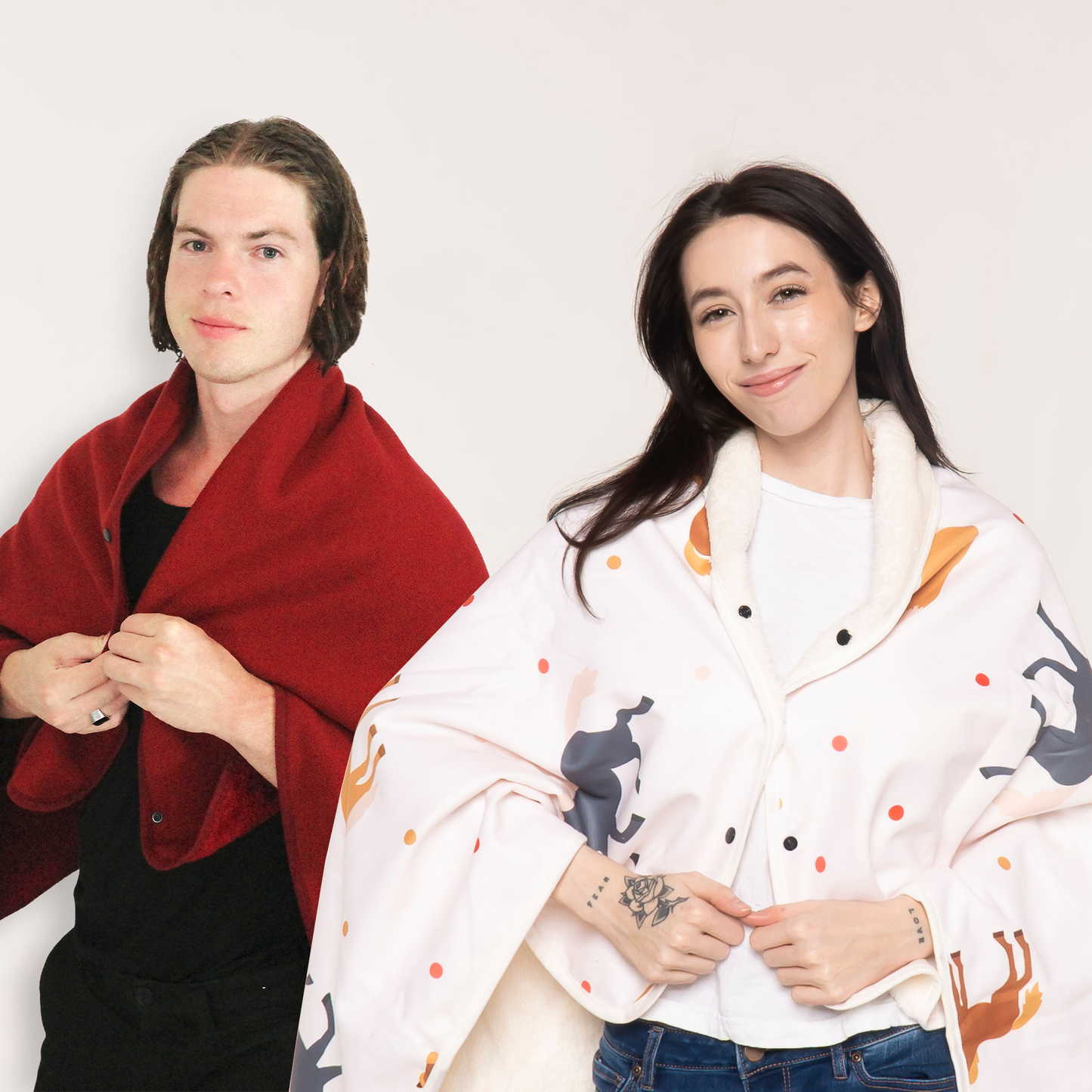 A man and a woman wearing matching wearable cape blankets from a twin bundle set. The man is draped in a solid deep red fleece wrap, while the woman wears a soft fleece cape with a horse-themed print. Perfect for couples, friends, or gift sets looking for stylish and cozy warmth.
