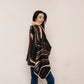 A stylish woman wearing a chocolate brown swirl fleece cape blanket with plush lining, ideal for lounging in warmth and comfort.