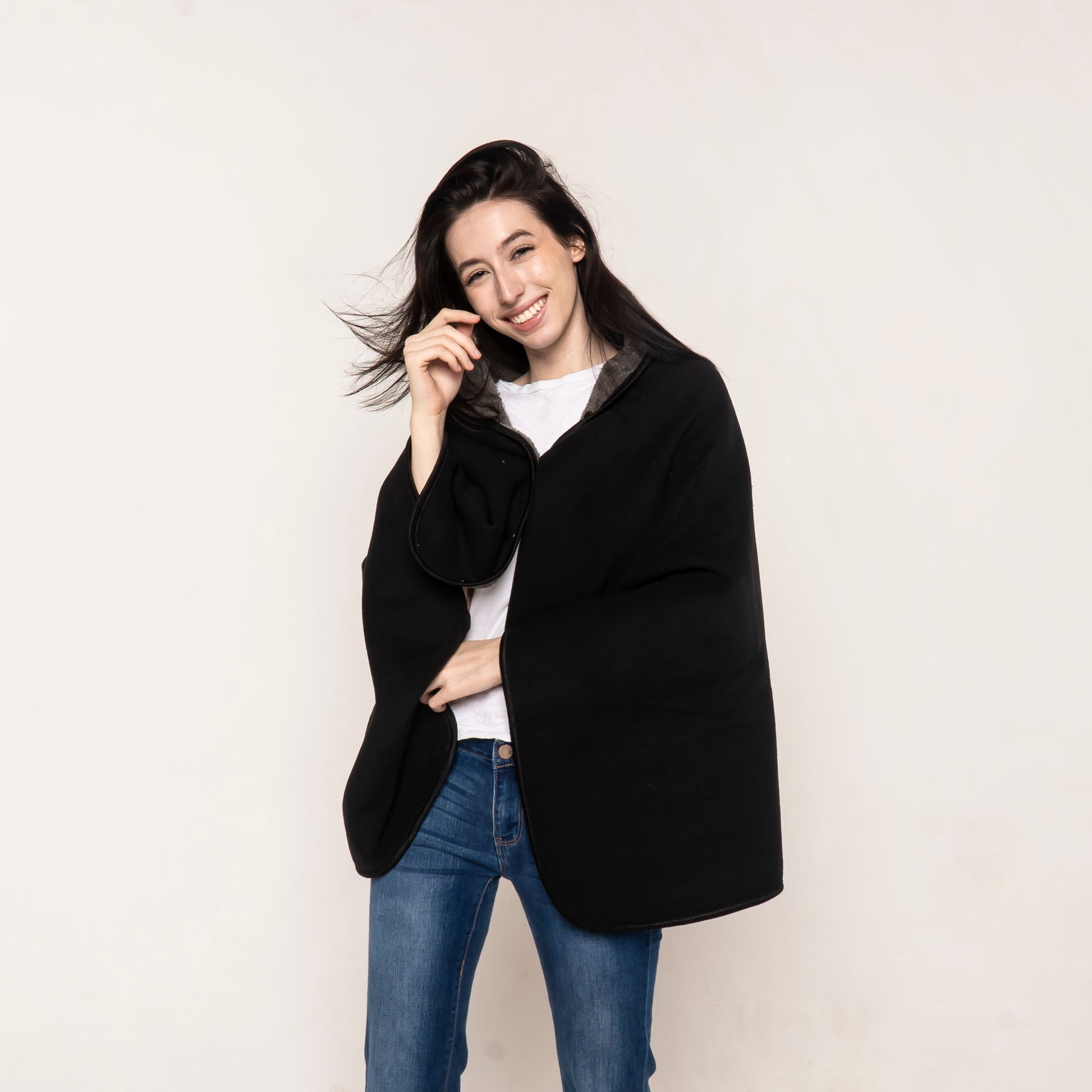 Model wearing a black fleece cape blanket with button closure, designed for ultimate warmth and style. A versatile and elegant wearable throw, reminiscent of a Batman cape.