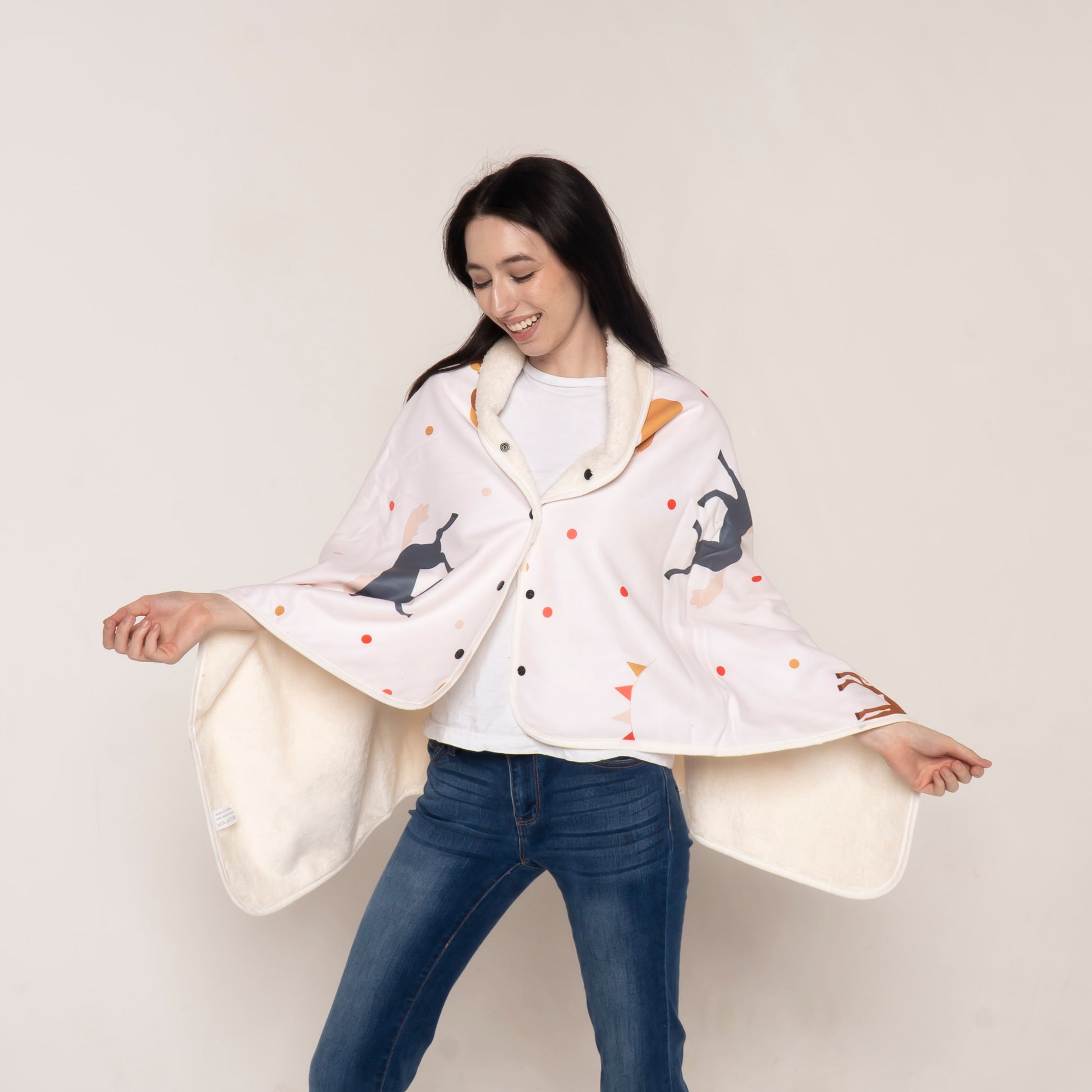 A smiling woman wearing a soft fleece cape blanket with a stylish horse print design, showcasing its warmth and elegance for equestrian enthusiasts.