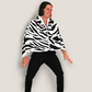 A man wearing the zebra print wearable blanket cape, showing off its stylish black-and-white animal print design. Made with ultra-soft fleece for warmth and comfort, perfect for lounging or making a bold fashion statement.